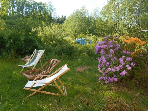 two lawn chairs sitting in the grass next to flowers at Au val des meuris in Taintrux