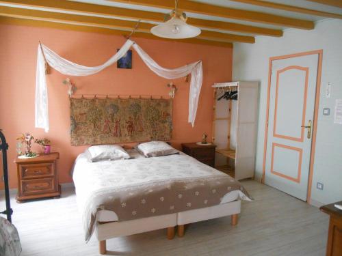 - une chambre avec un grand lit aux murs orange dans l'établissement Au val des meuris, à Taintrux