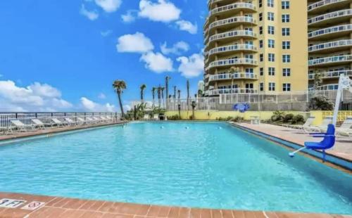 une grande piscine avec un bâtiment en arrière-plan dans l'établissement Ocean Side Inn Studios, à Daytona Beach