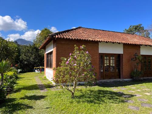a small brick house with a tree in the yard at Pousada Granja Santa Barbara in Petrópolis
