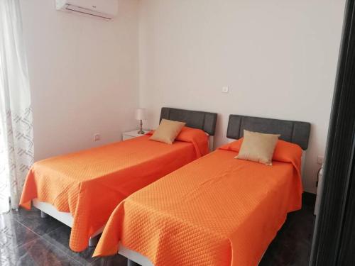 two beds with orange sheets in a room at Central, Fully Equipped Modern Apartment - 2 in Mġarr
