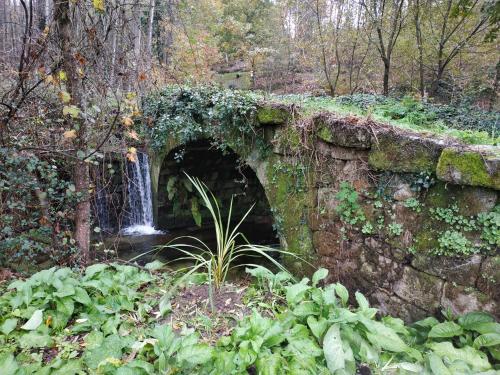 an ivy covered stone bridge with a waterfall at Quinta do Paúl de Baixo in Guimarães