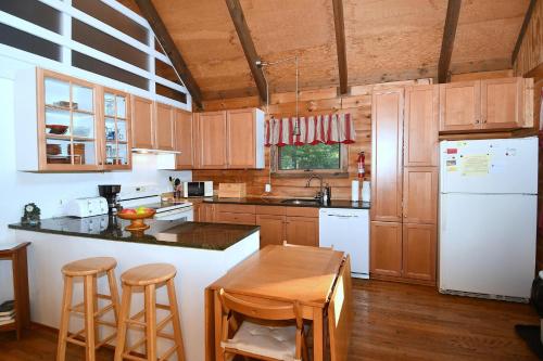 a kitchen with a white refrigerator and wooden cabinets at The Outlook - Pet Friendly, Grill, Wifi, View, Fire Pit, Deck, Family Friendly, Foosball, Game Room, King Bed, Fireplace in Morton Grove