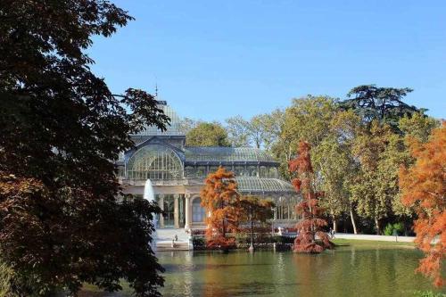 a large glass house with a pond in front of it at Apartamento IV AlcaláRetiro Ideal Parejas in Madrid