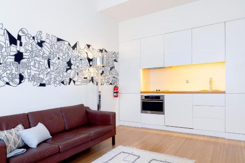 a living room with a brown couch and a kitchen at The Art Porto - Holiday Homes in Porto