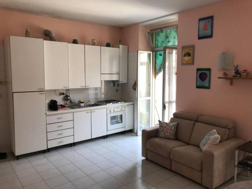 una cocina con armarios blancos y un sofá en una habitación en Appartamento Torino-zona Politecnico, en Turín