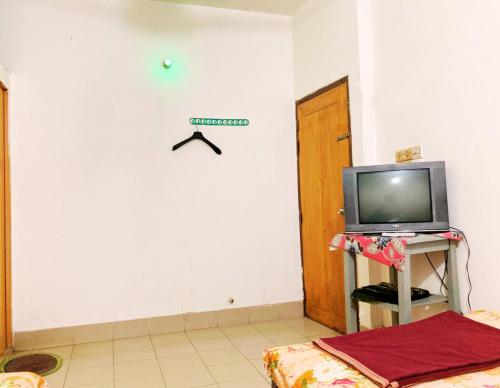 a room with a tv on a white wall at Mohammadia Restaurant & Guest House Near United Hospital in Dhaka