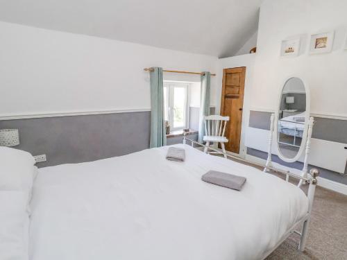 a bedroom with a white bed and a mirror at Carreg Cottage in Wrexham