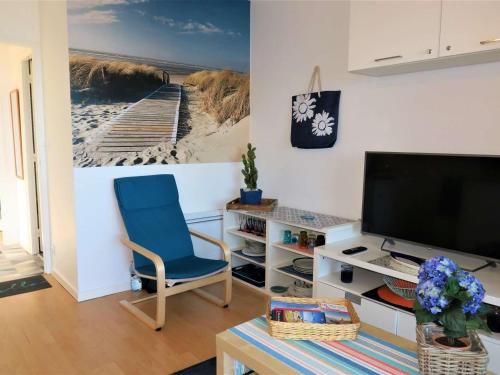 un salon avec une chaise bleue et une télévision dans l'établissement Appartement rénové avec jardin à 750m de la plage, WIFI et parking, Perros-Guirec - FR-1-368-194, à Perros-Guirec