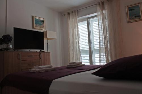 - une chambre avec un lit, une télévision et une fenêtre dans l'établissement Cozy Apartment Skalini, à Dubrovnik