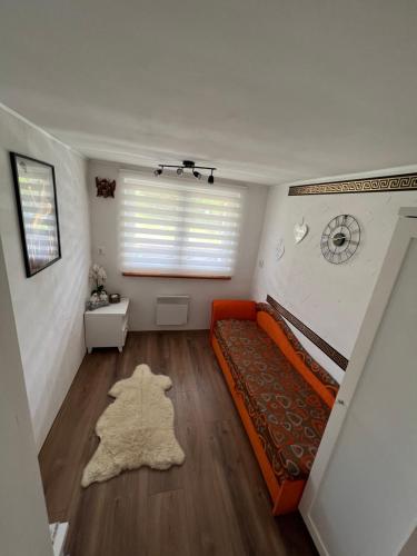 ein Wohnzimmer mit einem orangenen Sofa und einem Fenster in der Unterkunft Domek KALINKA -Góry Sowie-Rzeczka in Rzeczka