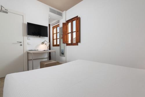 a white room with a bed and a television at HBE Boutique España - Turismo de Interior in Llucmajor