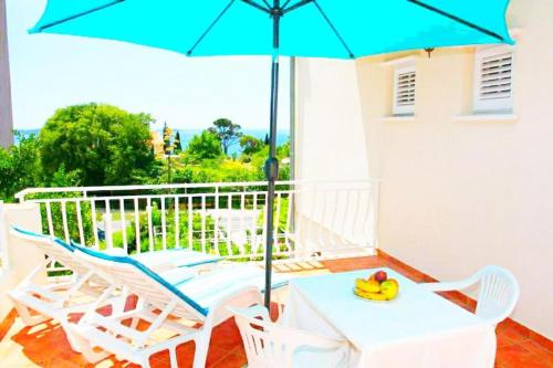 a table and chairs with a blue umbrella on a balcony at Apartments & Rooms Čakelić in Mlini