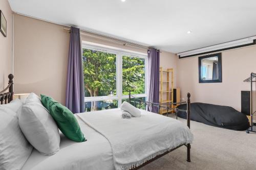 ein Schlafzimmer mit einem Bett und einem großen Fenster in der Unterkunft Modern Eco House With Parking in Brighton & Hove