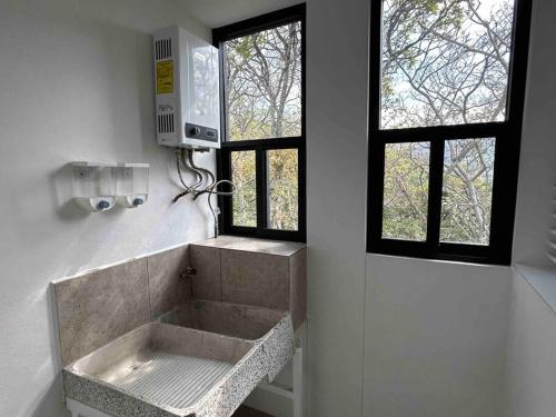 a bathroom with a sink and two windows at Lujoso Departamento in Mexico City