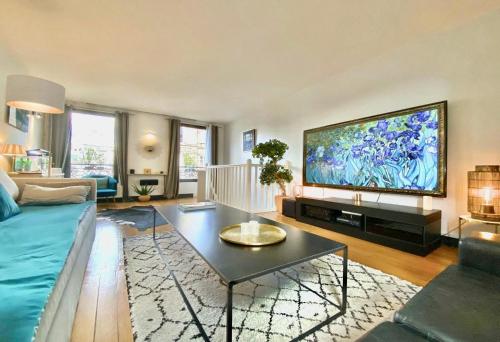 un salon avec une grande télévision à écran plat dans l'établissement LESPARISNORMANDS - le duplex de la reine, proche Parc des expositions porte de Versailles et Tour Eiffel, à Boulogne-Billancourt