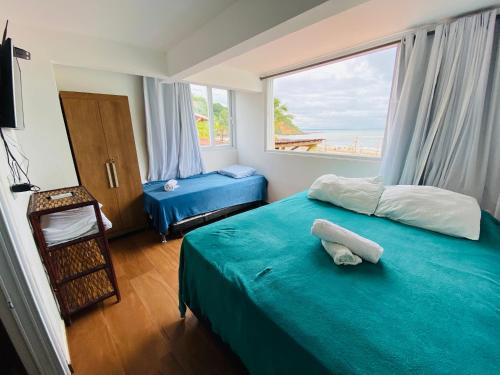 1 dormitorio con cama azul y ventana grande en Casa de Praia, en Morro de São Paulo