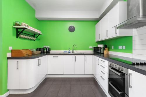 a kitchen with white cabinets and a green wall at Modern House with Parking Buisness and Leisure in Brighton & Hove