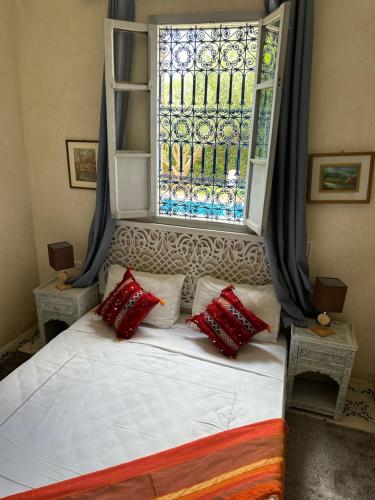 a bed with red pillows in front of a window at Oasis Merasi Marrakech in Marrakech