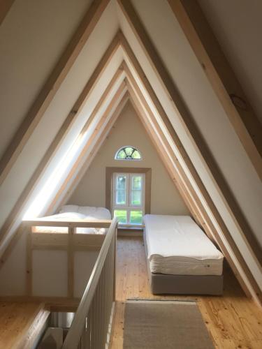 1 dormitorio en el ático con 2 camas y ventana en Gästehaus Weidenkörbchen en Jork