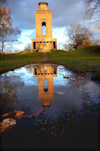 a reflection of a clock tower in a pond at Ferienwohnung Nachtigall in Burg