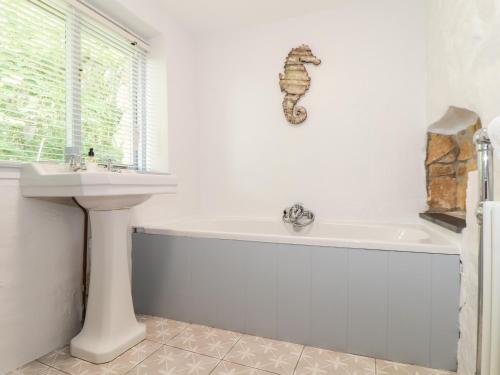 y baño con bañera y lavamanos. en Rockhopper Cottage en Penzance