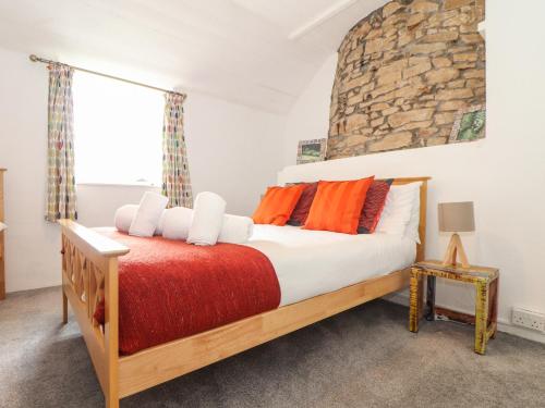 1 dormitorio con 1 cama grande con almohadas de color naranja en Rockhopper Cottage en Penzance