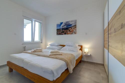 a white bedroom with a large bed and a window at Villa Panorama in Senj