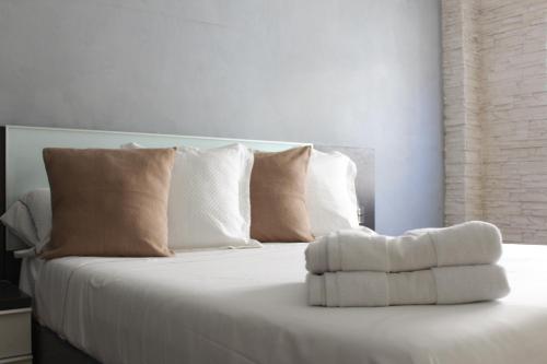 Una cama blanca con almohadas y toallas. en Apartamento Bahía, en Santa Pola