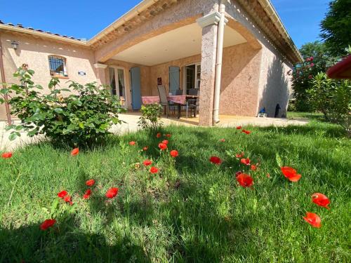 ein Feld voller roter Blumen vor einem Haus in der Unterkunft Villa de charme Mas de la Cigaline & chambres d'hôtes chez Dany 83 in Garéoult