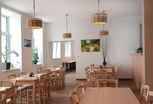 un restaurante con mesas y sillas de madera y ventanas en Penzion U Provazníka en Zdíkov
