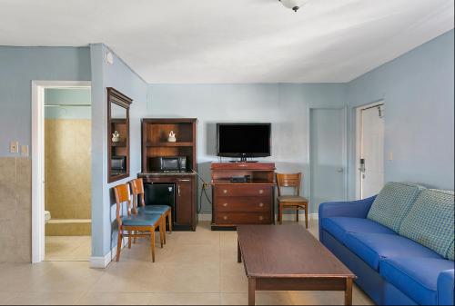 a living room with a blue couch and a tv at Deluxe Inn in Dania Beach