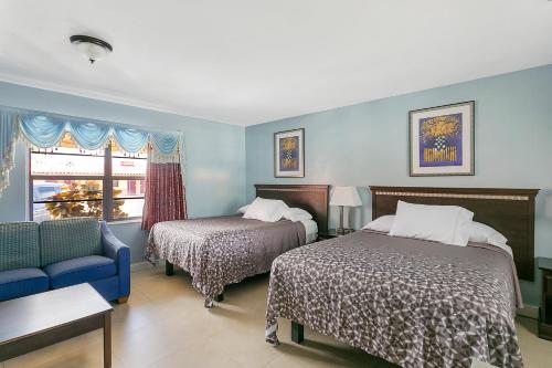 a bedroom with two beds and a couch and a window at Deluxe Inn in Dania Beach