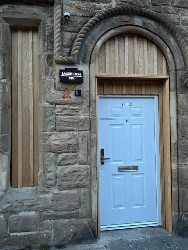 a blue door on a stone building with a gate at Laurieston Inn 