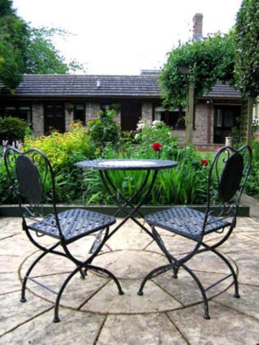 two chairs and a table in front of a garden at Fairlight Lodge in King's Lynn
