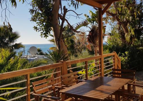 Villaggio Dei Fiori في سانريمو: بريغولا خشبي مع طاولة وكراسي على الشاطئ