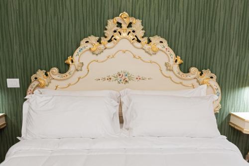 a bed with a gold and white headboard and white pillows at Residenza Catullo in Verona