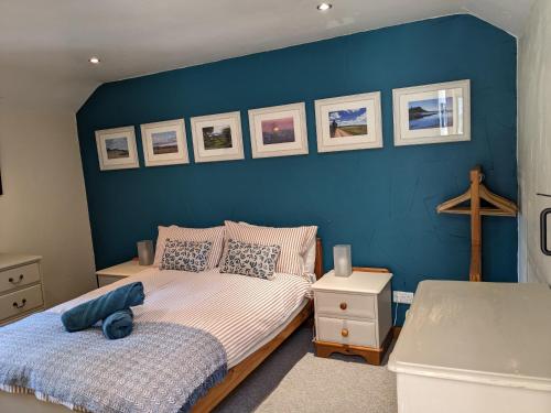 a bedroom with a blue wall with two beds at The Old Dairy in Bridport