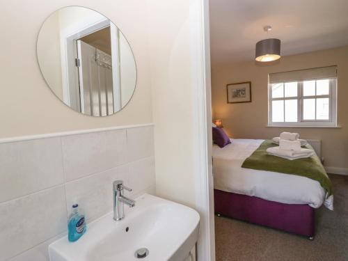 a bathroom with a sink and a mirror and a bed at Rolo's Retreat in Grange Over Sands