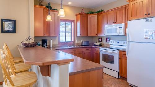 a kitchen with wooden cabinets and a white refrigerator at Trails Edge #03 By Bear Country in Sun Peaks