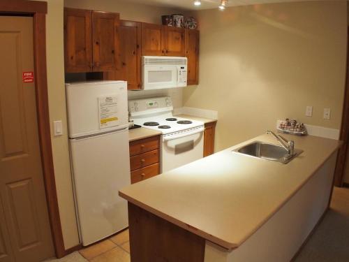 a kitchen with a white refrigerator and a sink at Fireside Lodge #302 By Bear Country in Sun Peaks