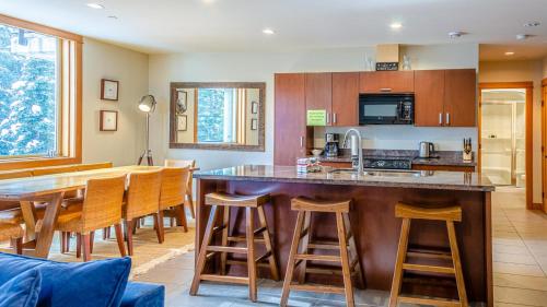 a kitchen with a bar and a table and chairs at Kookaburra Lodge #303 By Bear Country in Sun Peaks