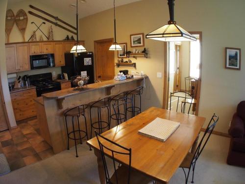 a kitchen with a wooden table and bar with chairs at Crystal Forest #66 By Bear Country in Sun Peaks