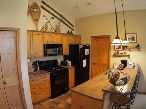 a kitchen with a black refrigerator and a stove top oven at Crystal Forest #66 By Bear Country in Sun Peaks