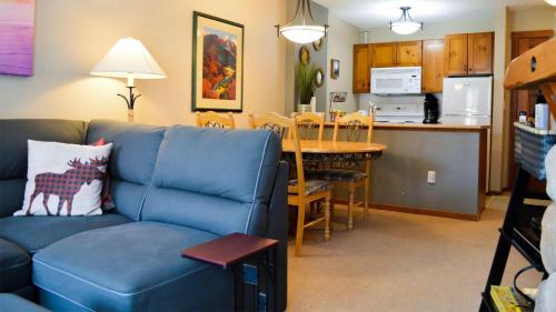 ein Wohnzimmer mit einem blauen Sofa und einer Küche in der Unterkunft Fireside Lodge #215 by Bear Country in Sun Peaks