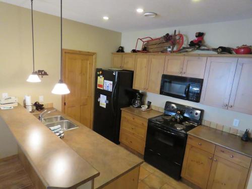 a kitchen with a black refrigerator and a sink at Crystal Forest #63 By Bear Country in Sun Peaks
