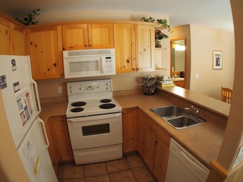 uma cozinha com um fogão branco forno ao lado de um lavatório em Crystal Forest #04 By Bear Country em Sun Peaks
