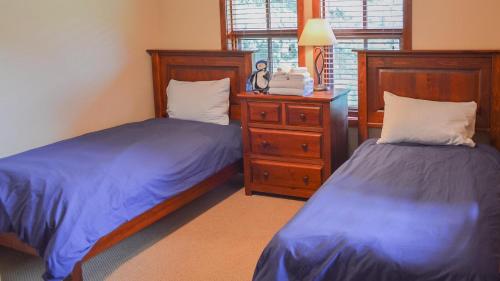 a bedroom with two beds and a dresser and a mirror at Woodhaven #18 by Bear Country in Sun Peaks