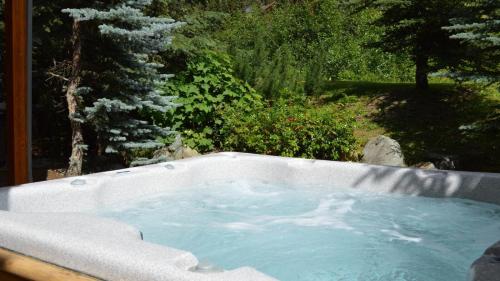 a hot tub in a garden with a tree at Woodhaven #18 by Bear Country in Sun Peaks