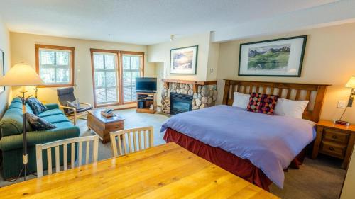 a bedroom with a bed and a couch and a fireplace at Fireside Lodge #223 By Bear Country in Sun Peaks